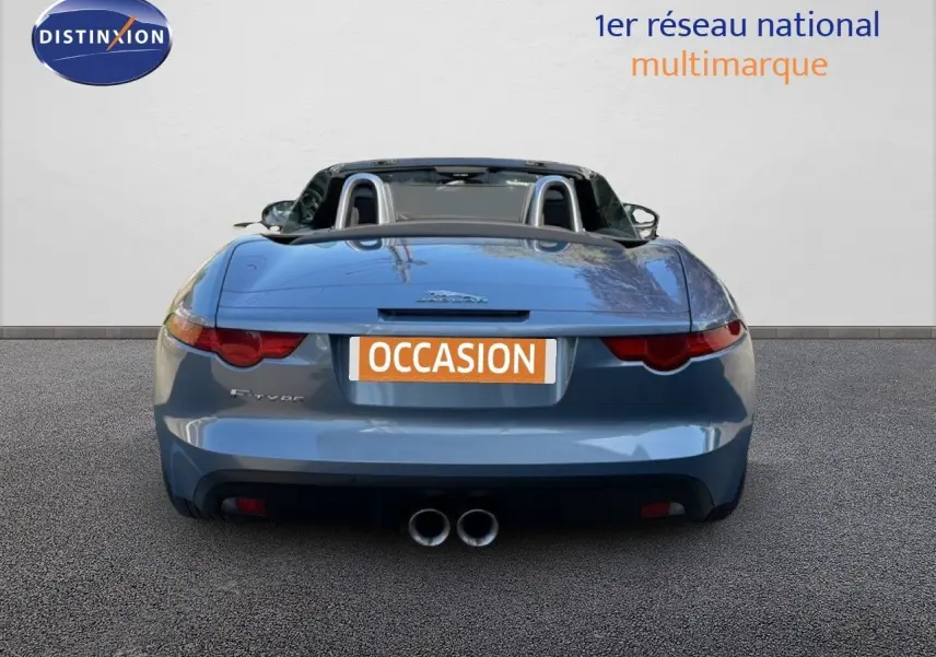 Vue arrière d'une Jaguar F-TYPE cabriolet gris 2013 avec double sortie d'échappement et arceaux de sécurité visibles.