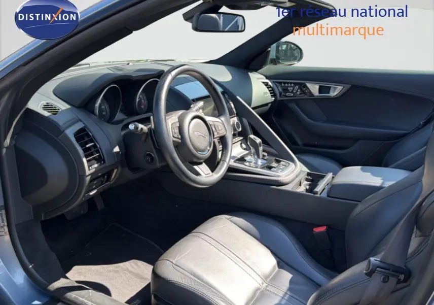 Vue intérieure côté conducteur de la Jaguar F-TYPE gris, mettant en valeur le volant cuir et la console centrale moderne.