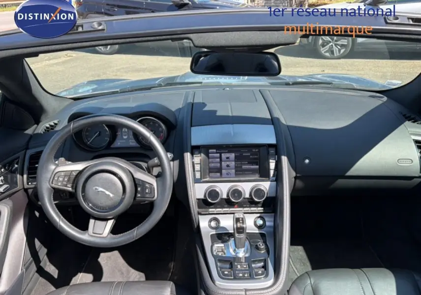 Vue intérieure avant de la Jaguar F-TYPE gris, tableau de bord avec écran tactile et volant cuir multifonctions.