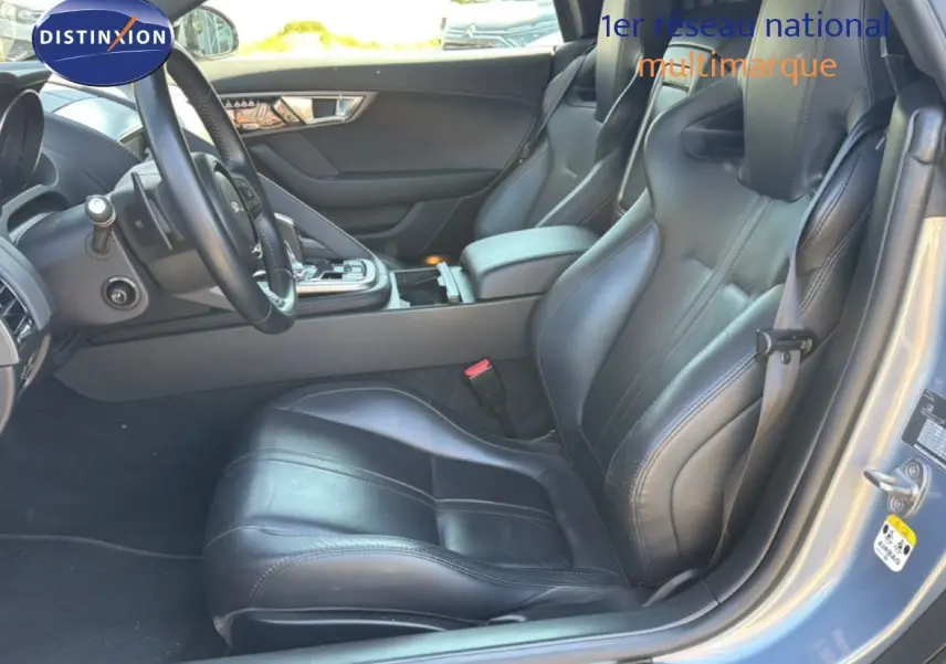Vue intérieure côté conducteur de la Jaguar F-TYPE 3.0 V6 gris, sièges sport cuir noirs et console centrale visible.