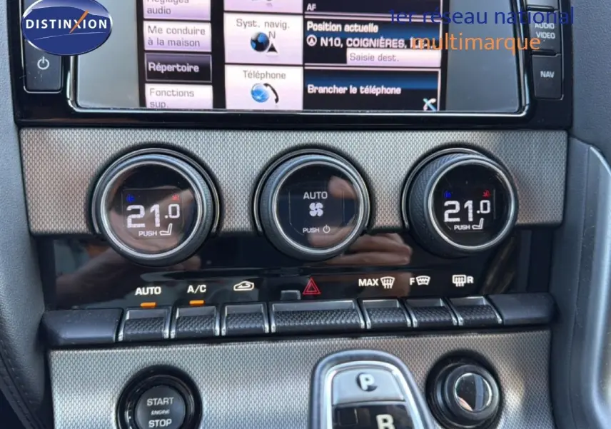 Gros plan sur la console centrale de la Jaguar F-TYPE gris, montrant les commandes de climatisation et le bouton start/stop.
