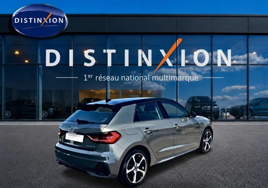 Audi A1 Sportback gris chronos avec toit noir, vue 3/4 arrière droit, jantes alu et becquet arrière visible.