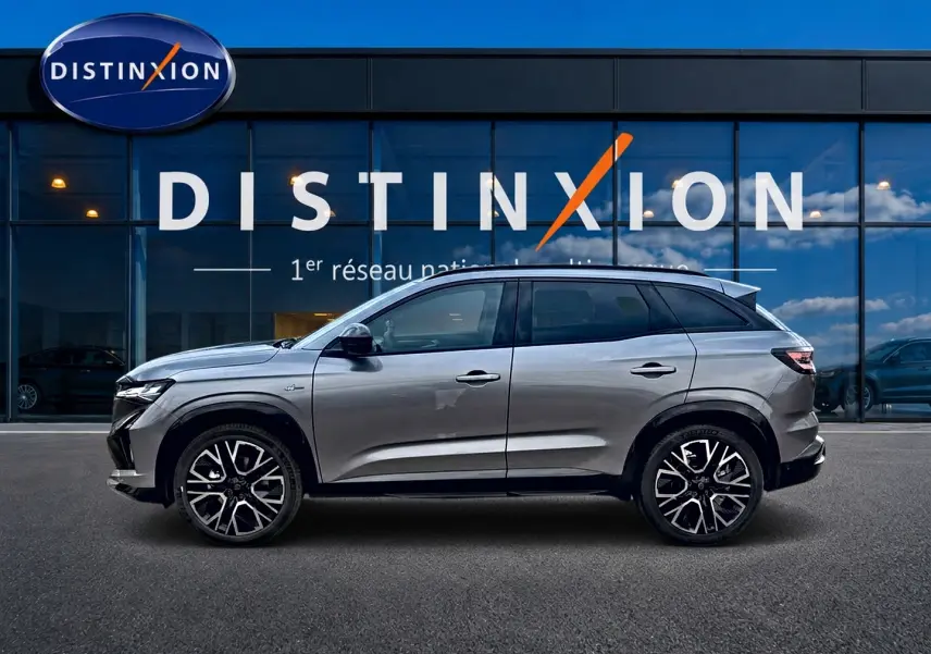 Profil droit du Renault Austral gris schiste 2026 devant une vitrine avec logo Distinxion visible.