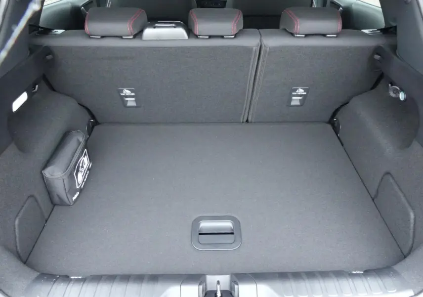 Coffre spacieux vu de l'arrière du Ford Puma 2025 gris métallisé avec sièges arrière rabattus et kit de réparation visible.