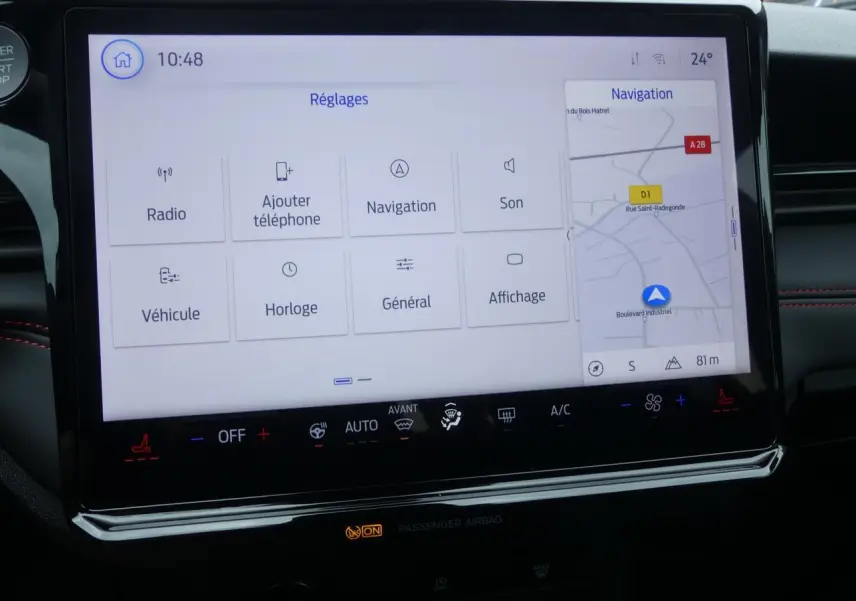 Écran tactile SYNC 4 de la Ford Puma 2025 montrant les réglages et la navigation, avec surpiqûres rouges visibles.