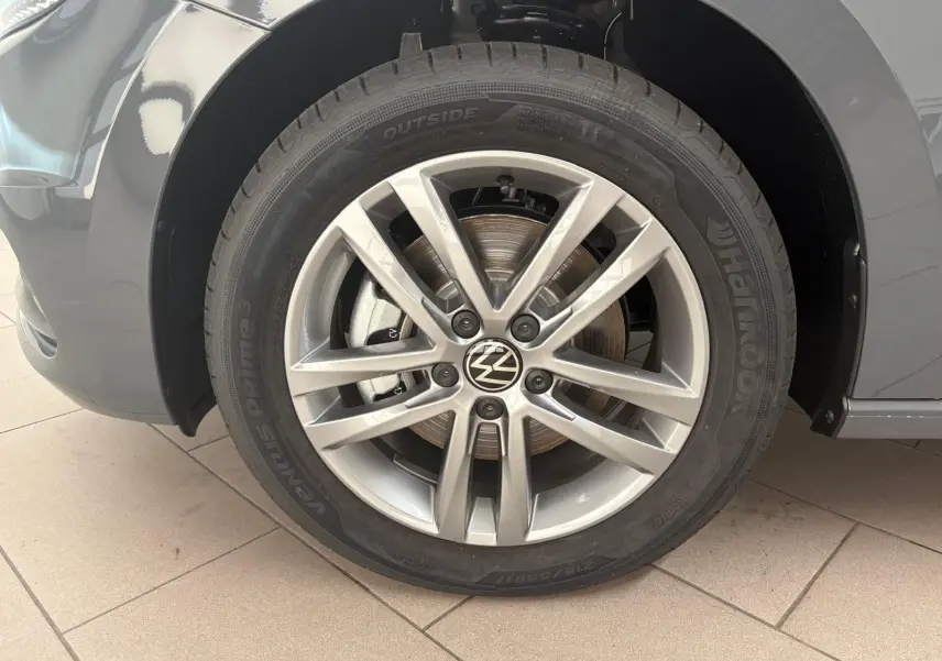 Gros plan sur la roue avant gauche du Volkswagen Touran gris dauphin avec jante alliage 17 pouces et logo VW central.