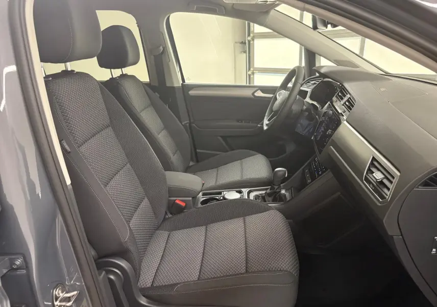 Intérieur avant du Volkswagen Touran gris dauphin 2025, sièges tissu gris et tableau de bord moderne côté droit.