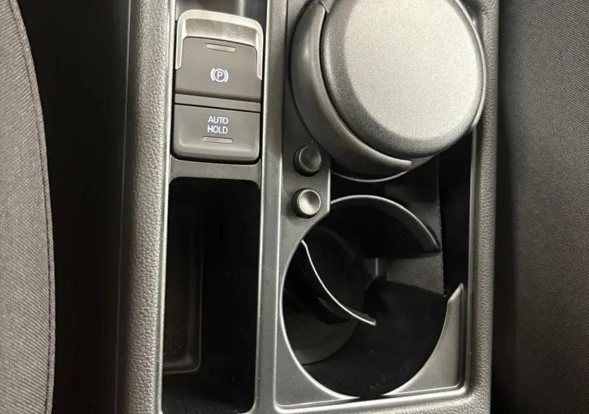 Gros plan sur la console centrale intérieure du Volkswagen Touran 2025, montrant le frein à main électronique et porte-gobelet.