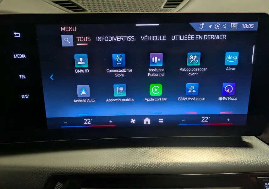 Écran tactile central du BMW X1 blanc 2025 affichant le menu principal avec options connectées et climatisation à 22°C.