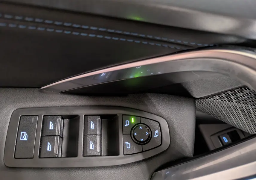 Gros plan sur les commandes des vitres électriques et rétroviseurs du côté gauche intérieur d'un BMW X1 blanc 2025.