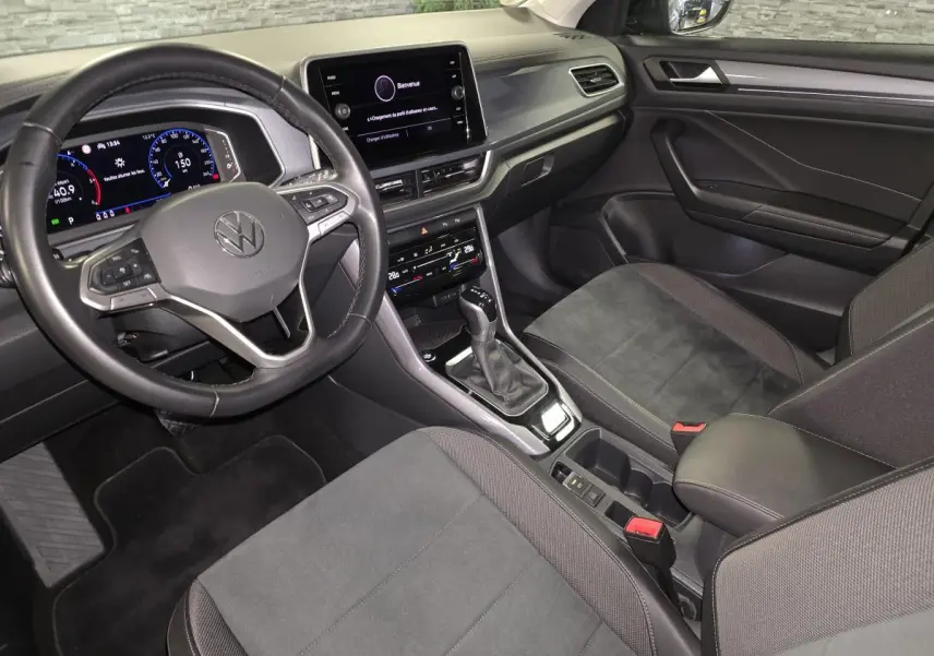 Intérieur noir du Volkswagen T-Roc 2022 vu côté conducteur, avec tableau de bord digital et écran tactile central.