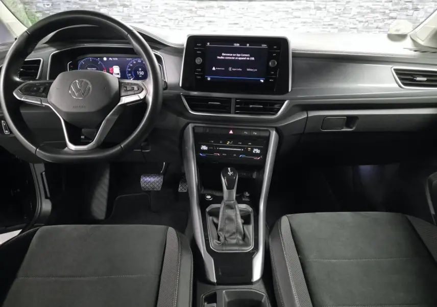 Vue intérieure avant du Volkswagen T-Roc 2022 noir, avec tableau de bord digital et écran tactile central.