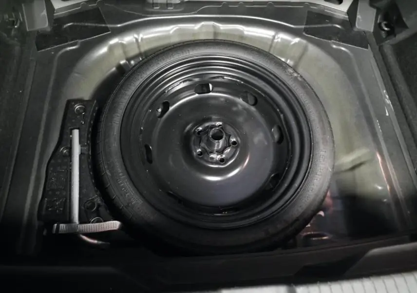 Vue plongeante sur la roue de secours compacte noire dans le coffre du Volkswagen T-Roc 2.0 TDI 2022.