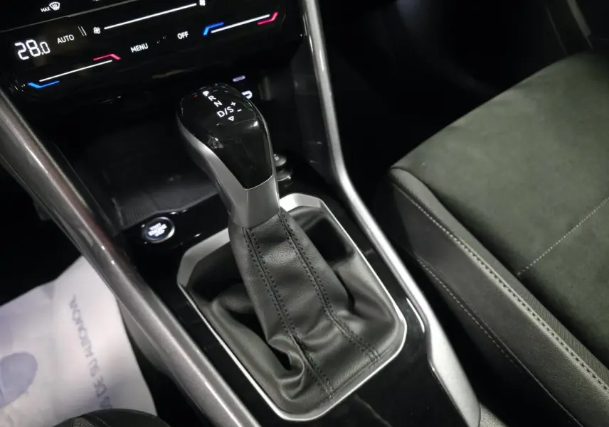 Gros plan sur la console centrale du Volkswagen T-Roc 2022, levier de vitesse automatique noir et sellerie Artvelours.
