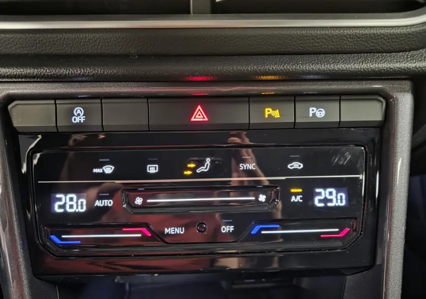 Gros plan sur la console centrale noire du Volkswagen T-Roc 2022, affichant la climatisation bi-zone réglée à 28 et 29 degrés.