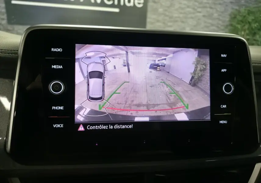 Écran tactile intérieur montrant la caméra de recul du Volkswagen T-Roc noir, avec lignes de guidage vertes et rouges.