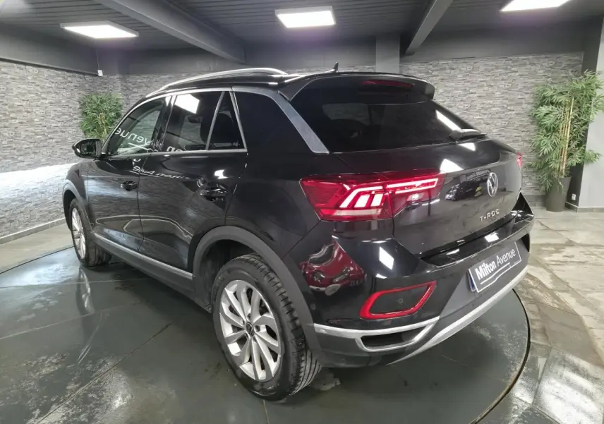 Vue 3/4 arrière droite du Volkswagen T-Roc noir 2022 avec feux LED et jantes alliage 17 pouces dans un showroom.