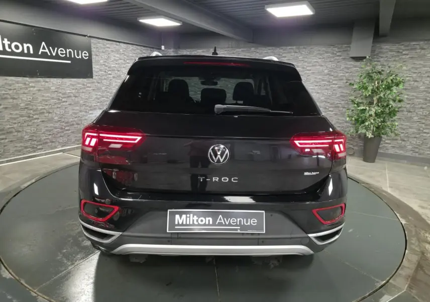 Vue arrière d'un Volkswagen T-Roc noir 2022 avec feux LED allumés dans un showroom intérieur.