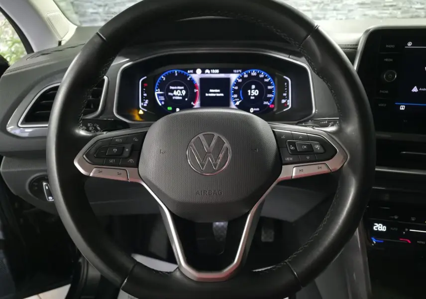 Vue rapprochée du volant en cuir noir multifonction du Volkswagen T-Roc 2022 avec tableau de bord digital lumineux.