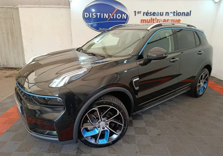 Vue 3/4 avant droite d'un SUV LINK & CO 01 noir avec jantes noires et bleues, dans un showroom intérieur.