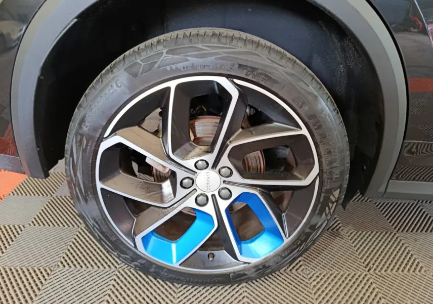 Gros plan sur la roue avant droite noire et bleu métallisé du SUV LINK & CO 01 hybride rechargeable 2023.