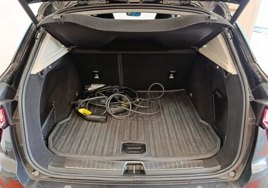 Coffre ouvert d’un SUV Link & Co 01 noir, vue arrière, avec câble de recharge hybride visible au sol.