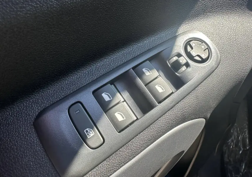 Gros plan sur les commandes des vitres électriques et rétroviseurs sur la porte avant gauche du Citroën Berlingo Sirkka Green.