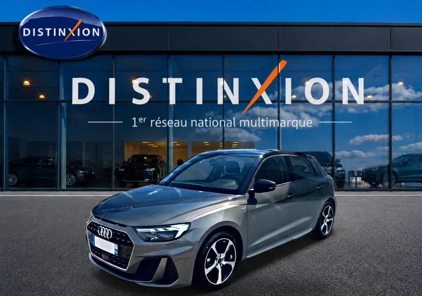 Audi A1 Sportback gris chronos vue 3/4 avant droit devant une vitrine Distinxion, jantes alu et toit noir.