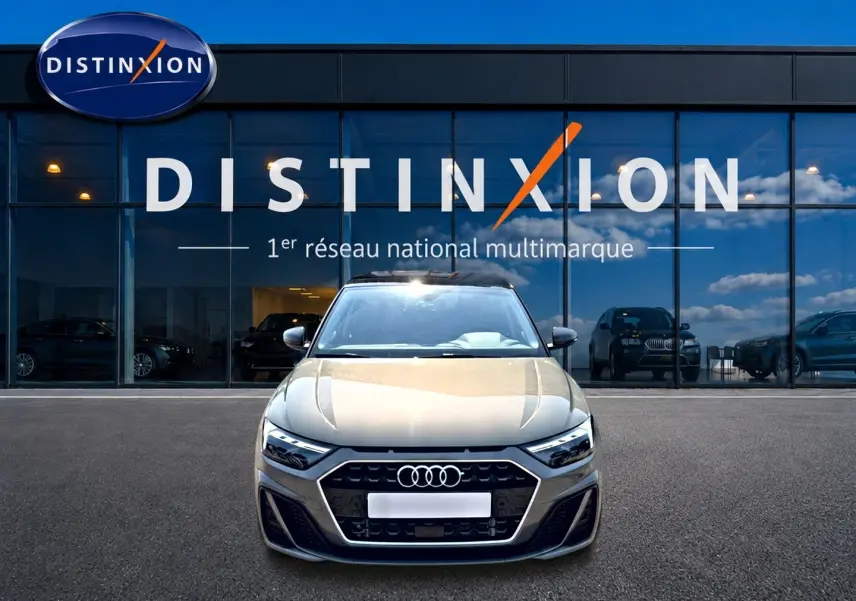 Vue de face d'une Audi A1 Sportback gris chronos avec toit noir, devant une vitrine Distinxion.