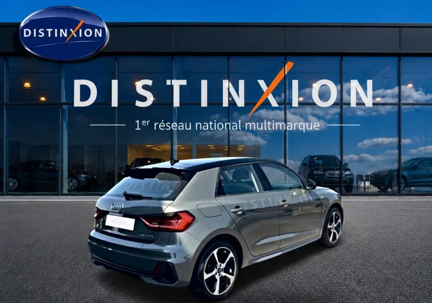 Audi A1 Sportback gris chronos vue 3/4 arrière droit avec jantes alu et toit noir devant showroom Distinxion.