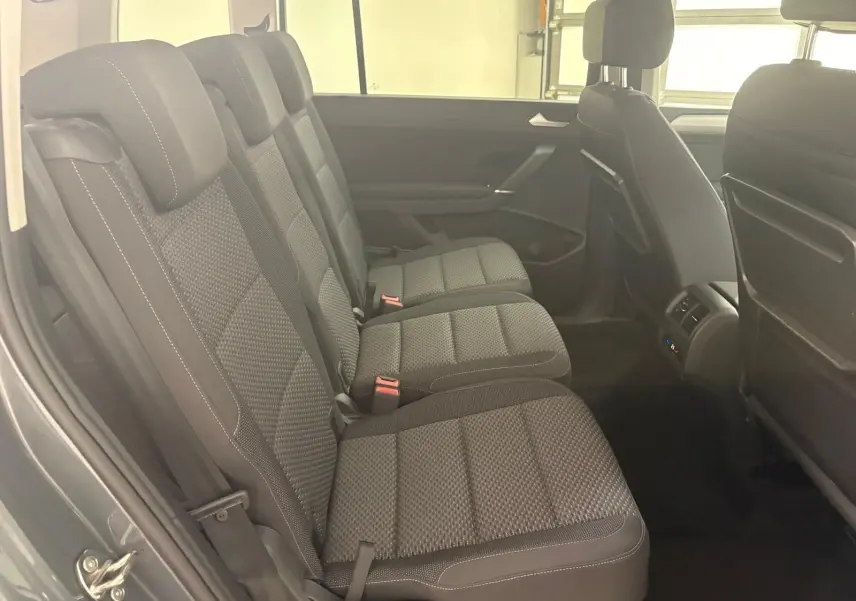Vue latérale des sièges arrière en tissu gris du Volkswagen Touran 2025, avec appuie-têtes et ceintures visibles.