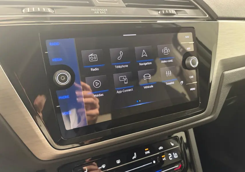 Écran tactile central du Volkswagen Touran 2025 gris dauphin, affichant les options multimédia et aides à la conduite.