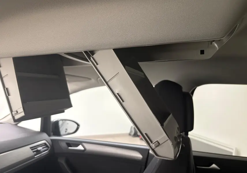 Détail de l'écran rabattable pour passagers arrière dans l'habitacle du Volkswagen Touran gris dauphin 2025.