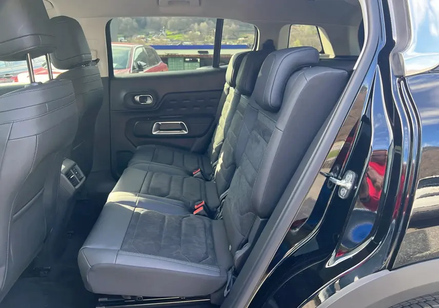 Vue latérale droite de l'intérieur arrière du Citroën C5 Aircross Hybrid 2025 noir, montrant les sièges en tissu et cuir.