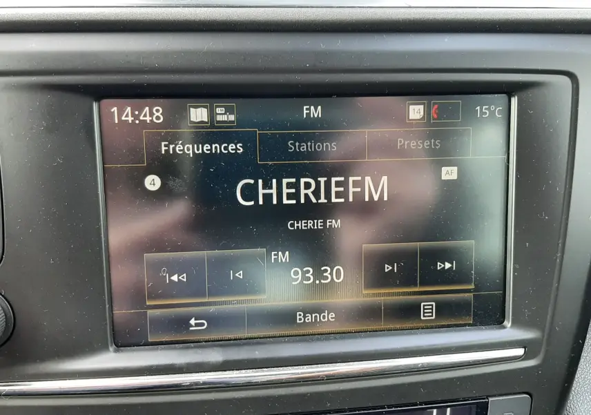 Vue rapprochée de l'écran multimédia et de la climatisation du Renault Kadjar gris, affichant la radio sur CHERIE FM 93.30.