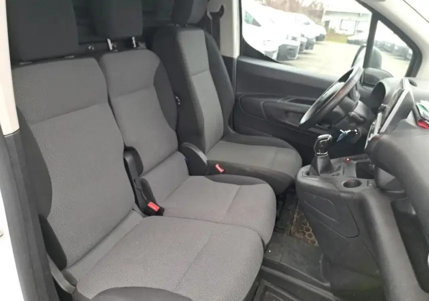 Vue intérieure côté conducteur du Citroën Berlingo blanc 2019, montrant les sièges gris et la console avec boîte manuelle.