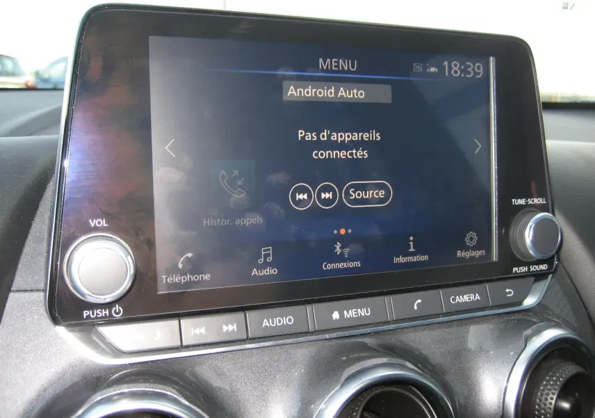 Vue rapprochée de l’écran tactile central du Nissan Juke 1.6 Hybrid 143 Tekna avec commandes audio et climatisation.