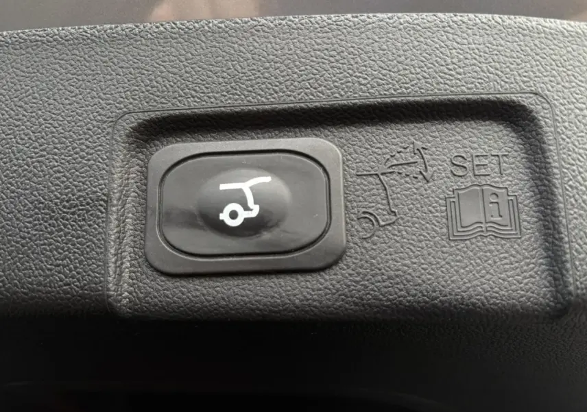 Bouton noir de hayon électrique avec pictogramme blanc, intégré dans le panneau intérieur du Ford Puma gris Solar 2023.