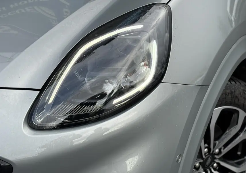 Gros plan sur le phare avant gauche et la jante alliage 17 pouces du Ford Puma gris Solar avec peinture métallisée.