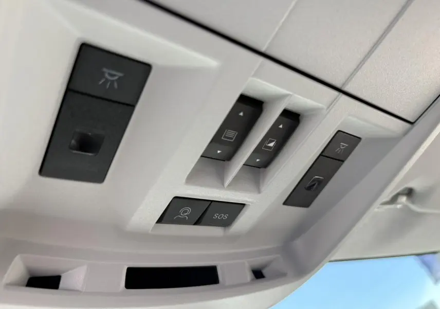 Vue en gros plan des commandes du toit ouvrant et des boutons SOS dans l'habitacle clair du Citroën C5 Aircross noir Perla.