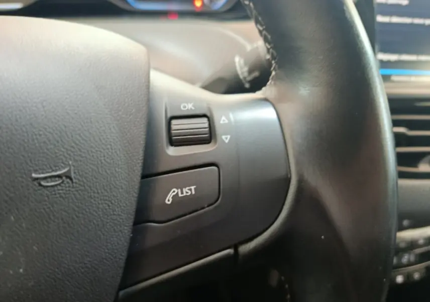 Gros plan sur le volant cuir noir de la Peugeot 2008 2019, avec commandes multifonctions visibles.