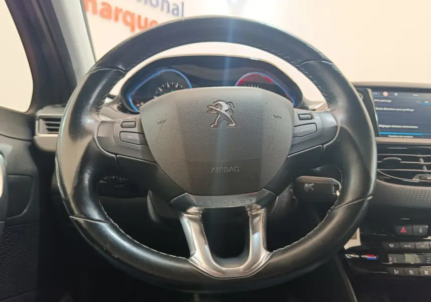 Vue rapprochée du volant cuir noir multifonctions du Peugeot 2008 gris foncé avec tableau de bord et écran tactile visibles.