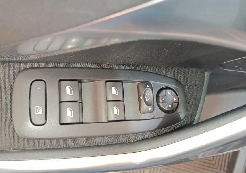 Gros plan sur les commandes des vitres et rétroviseurs côté conducteur d'une Peugeot 2008 gris foncé, version 2019.