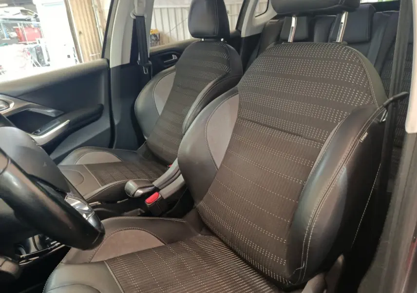 Vue intérieure côté gauche montrant les sièges avant en tissu et cuir noir du Peugeot 2008 gris foncé.