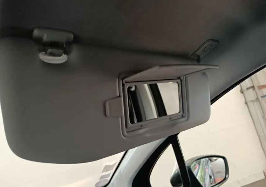 Détail du pare-soleil côté conducteur avec miroir de courtoisie ouvert dans une Peugeot 2008 gris foncé.