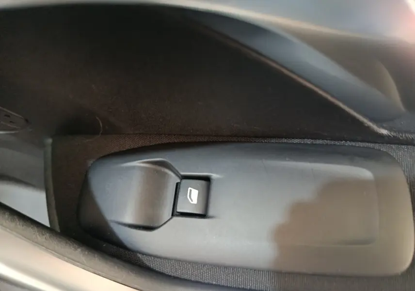 Gros plan sur le bouton de commande de lève-vitre côté conducteur d’un Peugeot 2008 gris foncé de 2019.