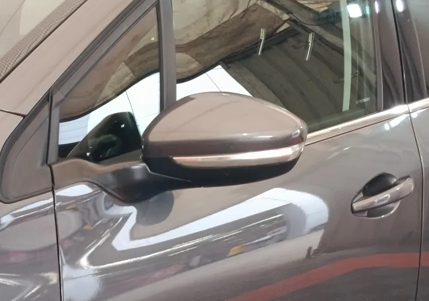 Gros plan sur le rétroviseur côté gauche et la portière gris foncé d'un Peugeot 2008 2019 stationné en intérieur.