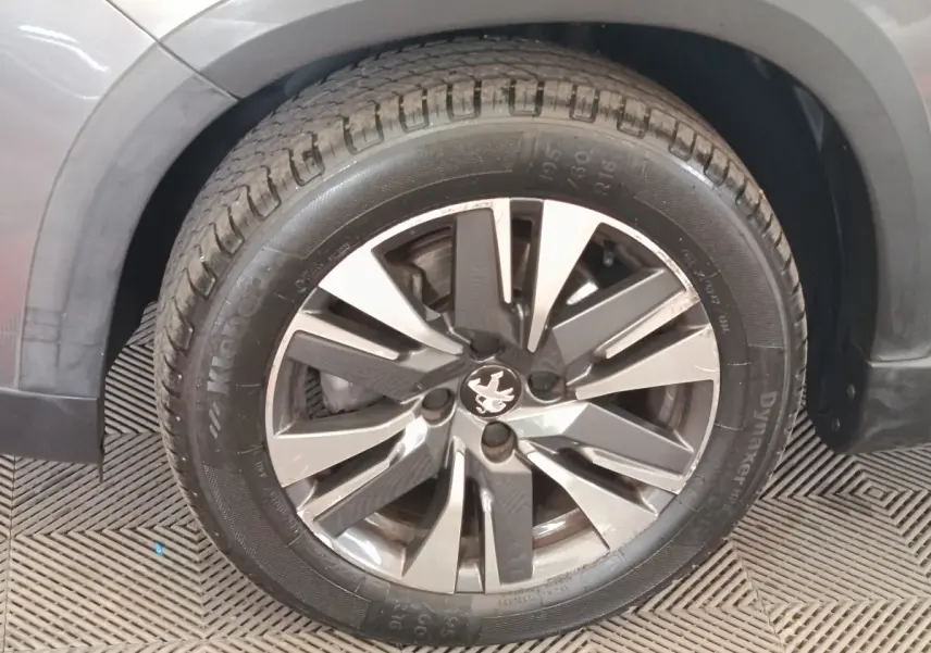 Gros plan sur la roue avant gauche d’un Peugeot 2008 gris foncé, mettant en valeur la jante alliage distinctive.