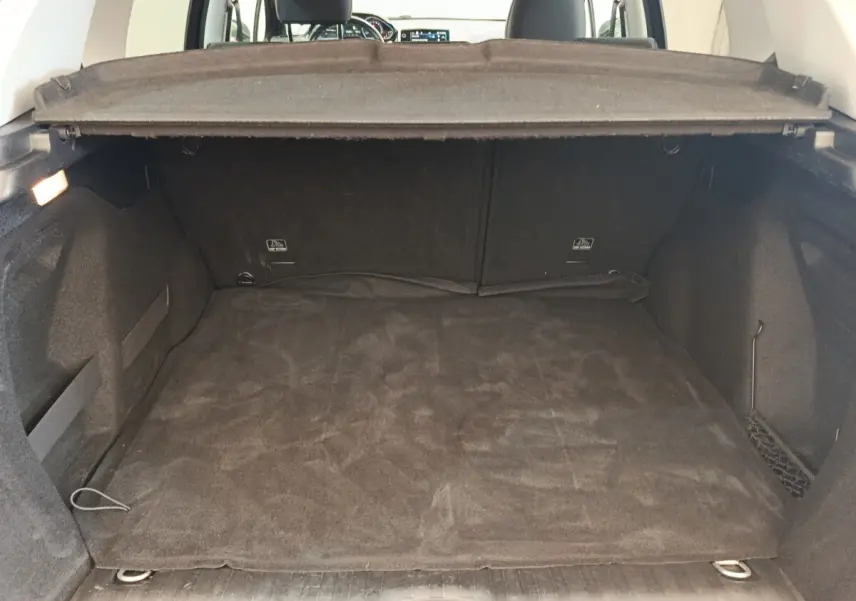 Coffre spacieux et propre du Peugeot 2008 gris foncé, vue depuis l'arrière avec la tablette de coffre relevée.