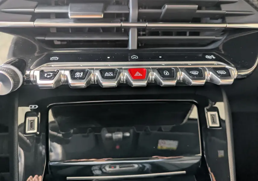 Gros plan sur la console centrale du Peugeot 2008 Hybrid 145, boutons métalliques et écran tactile noir brillant.